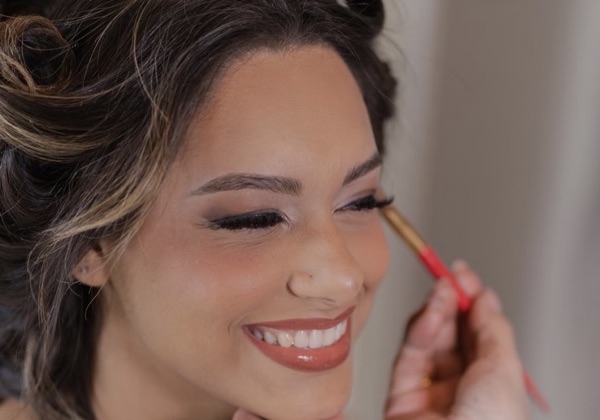 Une mariée souriante pendant la mise en beauté de ses yeux au pinceau